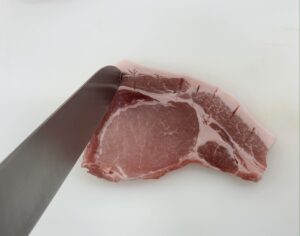 豚肉は、赤身と脂身の間に包丁の先で突くように切り込みを入る。